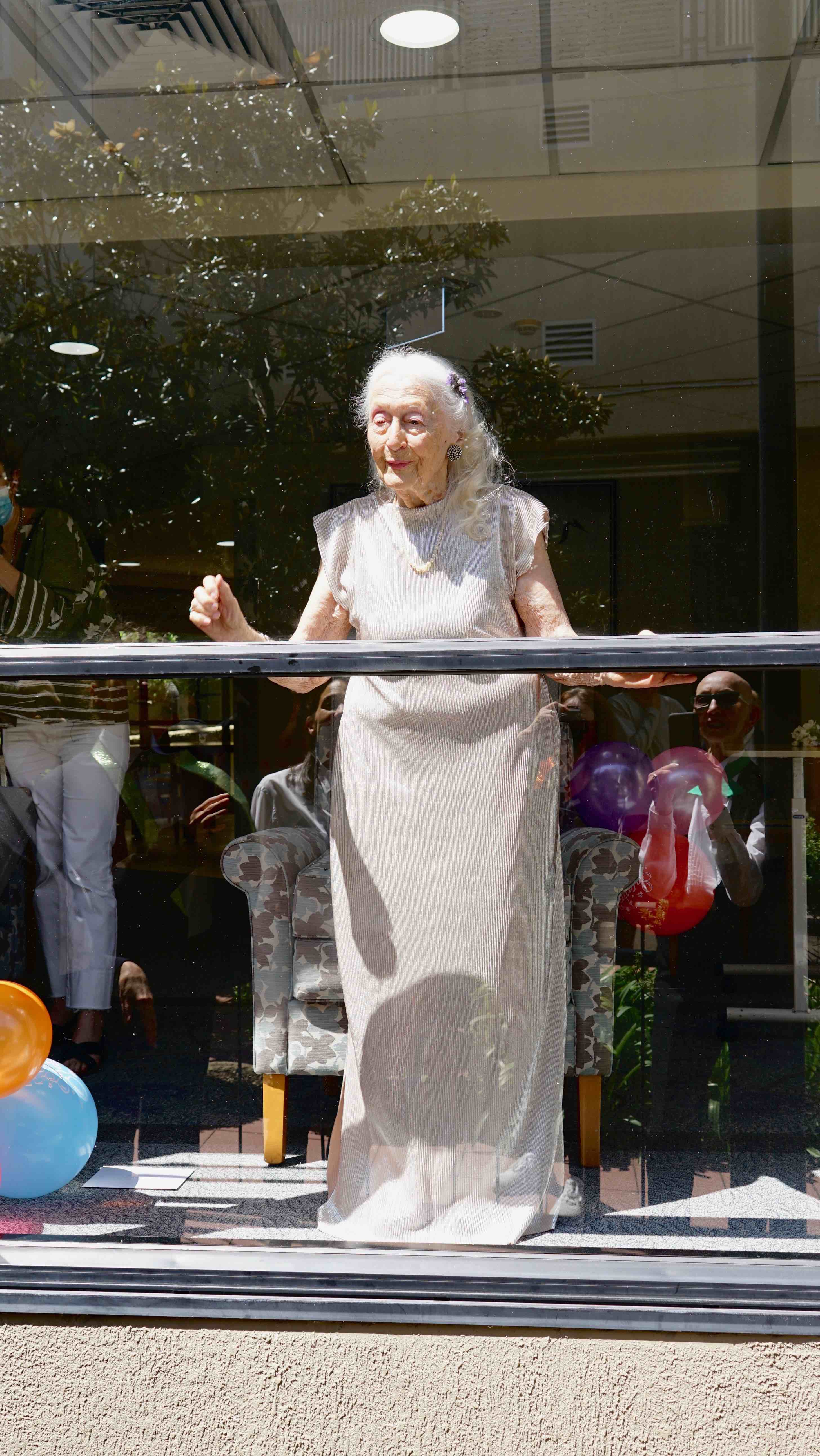 Eileen stands at the window ready to watch the performance.