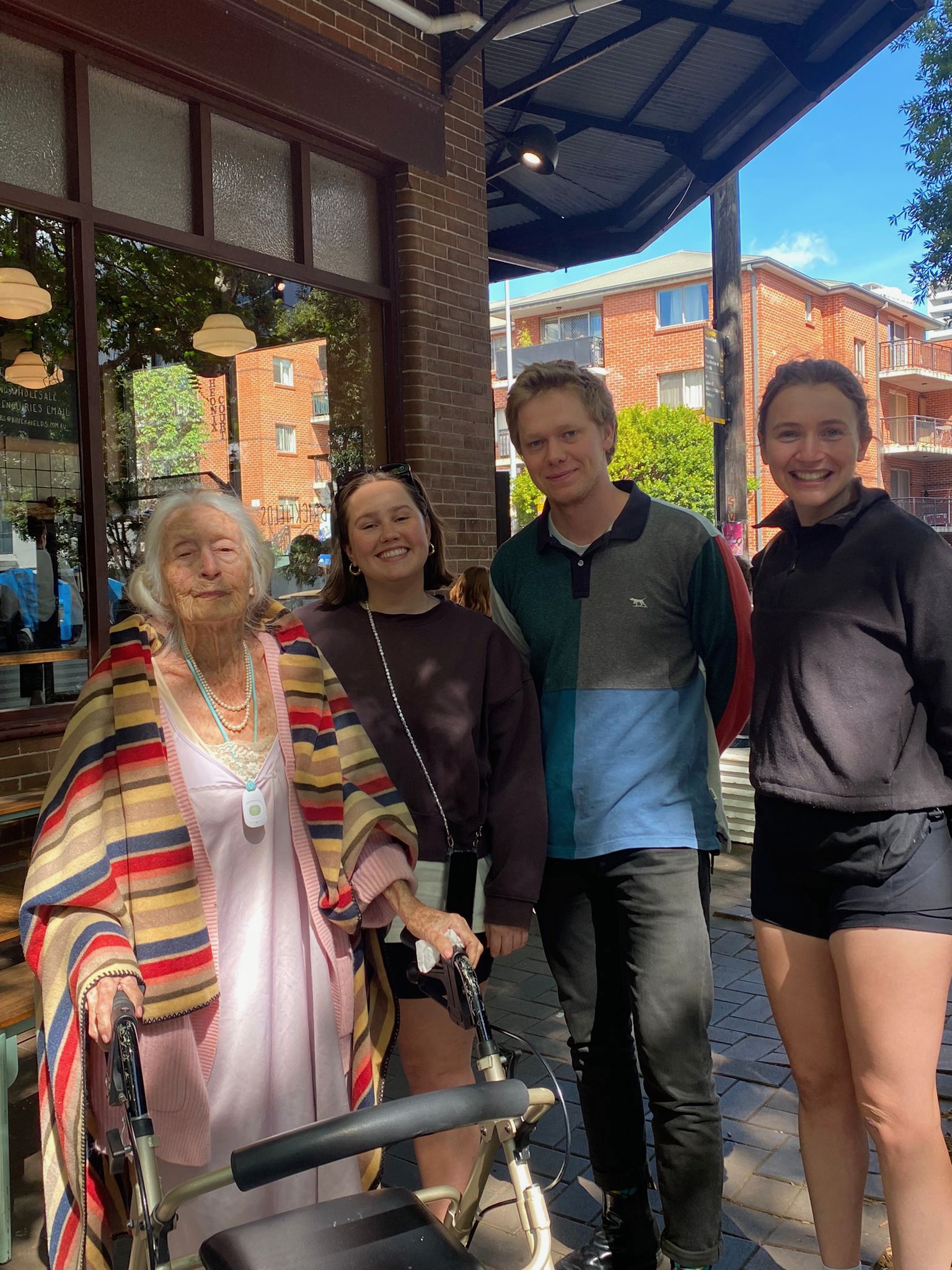 Eileen standing in front of Brickfields cafe with two young women and a young man.