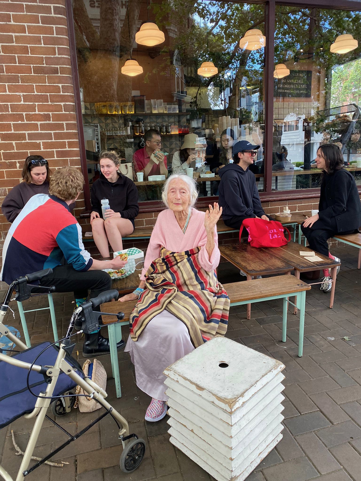 Eileen sitting on a bench outside Brickfields with other cafe customers.