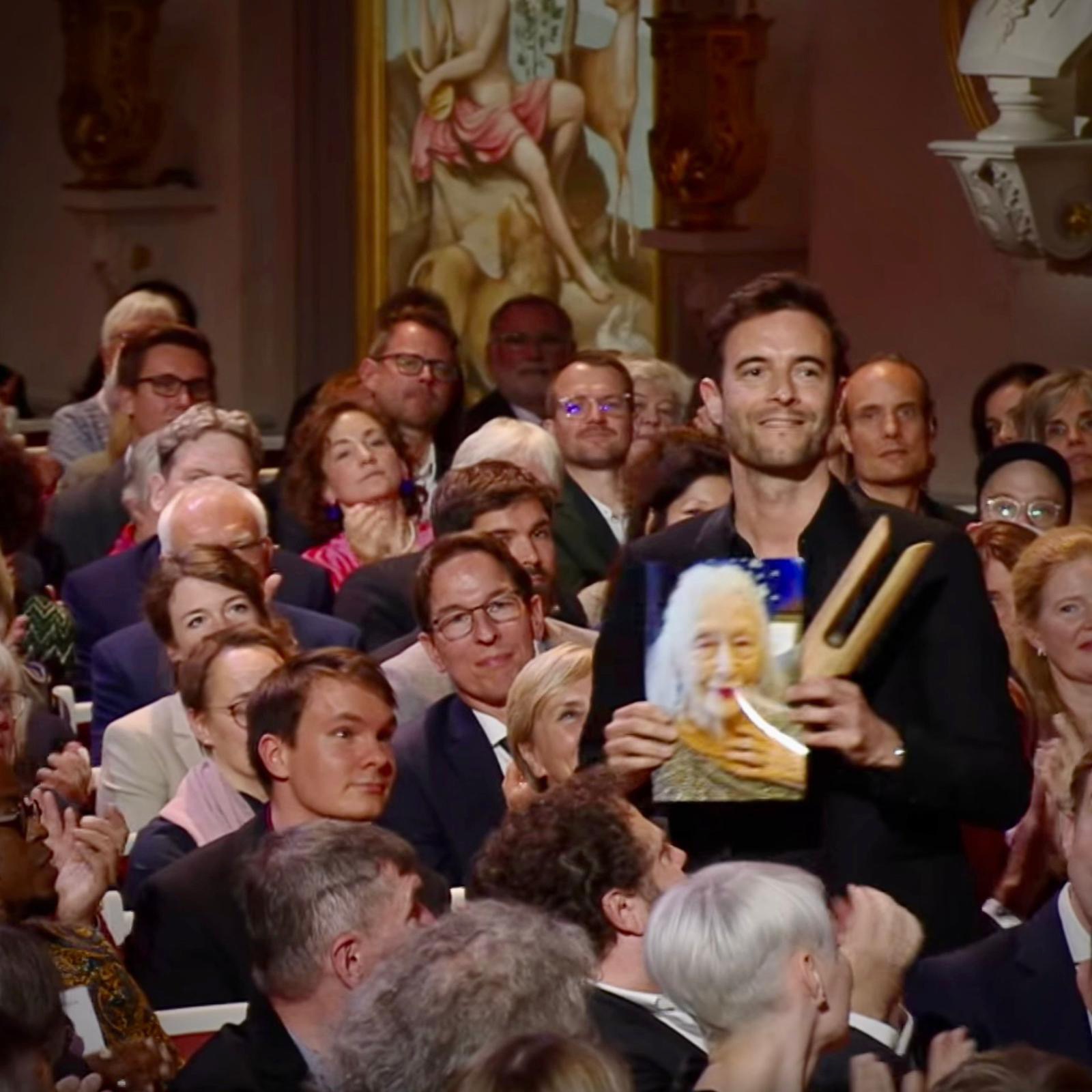 David Orlovsky in the audience holding his Opus Klassik award and a photograph of Eileen.